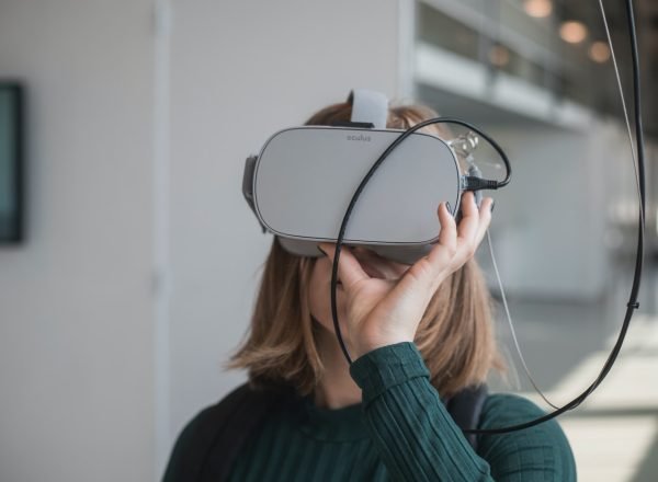 woman in black sweater holding white and black vr goggles